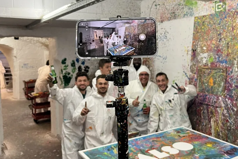 Action-painting sessie bij Splatter Studio Antwerpen — teams gooien en spuiten verf op een gezamenlijk doek